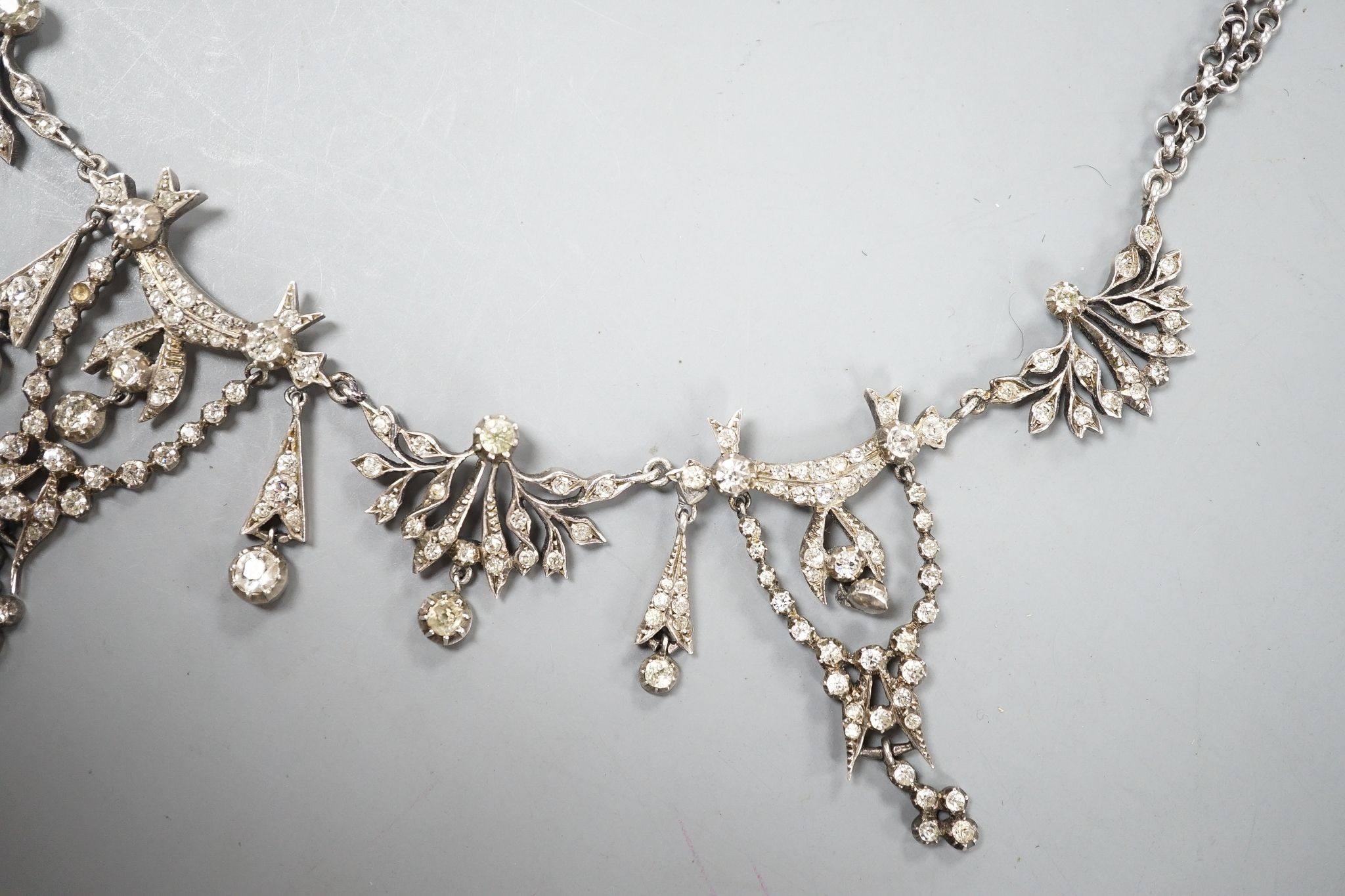 A 19th century white metal and paste set drop necklace, 37.5cm, in an associated gilt tooled fitted leather box.